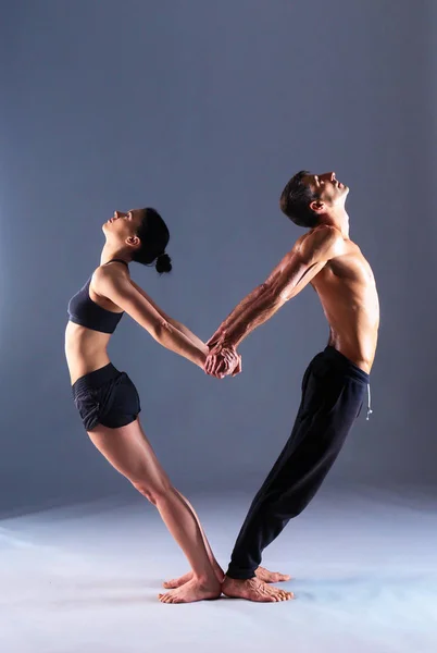 Young couple practicing acro yoga in studio together
