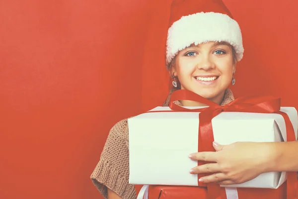 Santa flicka håller julklapp på röd bakgrund — Stockfoto