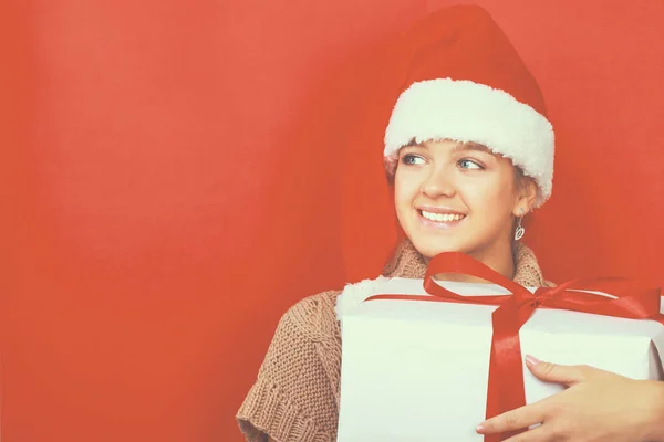 Santa flicka håller julklapp på röd bakgrund — Stockfoto