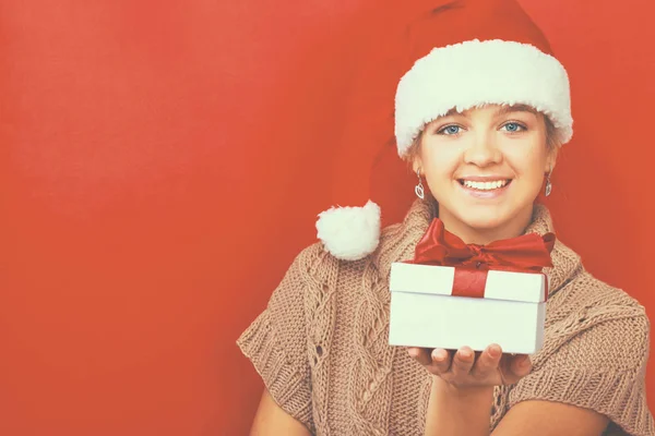 Santa flicka håller julklapp på röd bakgrund — Stockfoto