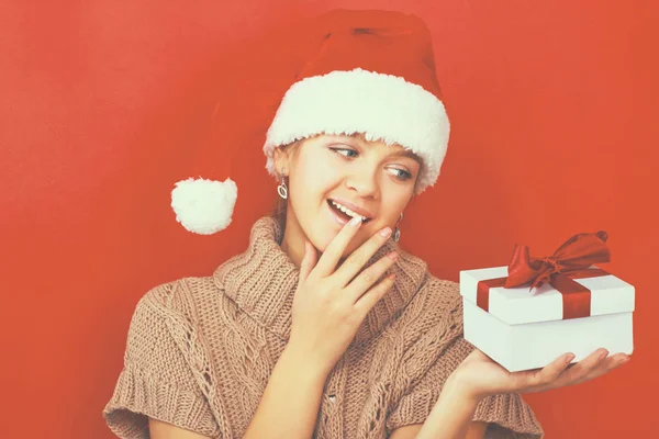 Santa flicka håller julklapp på röd bakgrund — Stockfoto