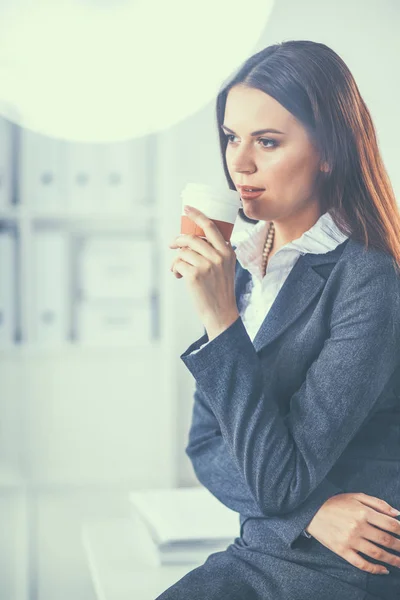 Mooie zakenvrouw genieten van koffie in helder kantoor — Stockfoto