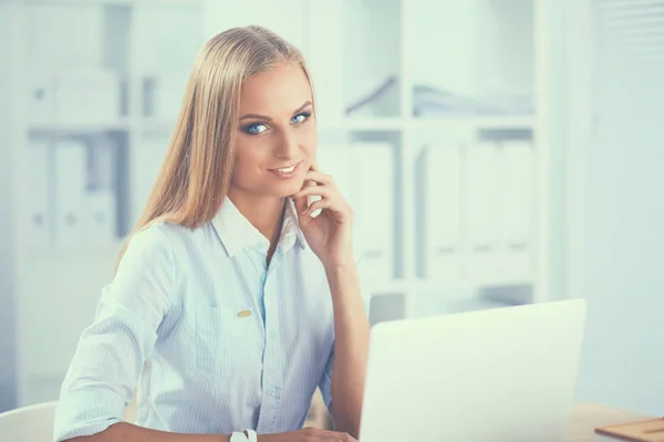 Aantrekkelijke zakenvrouw zit op een bureau met laptop in het kantoor — Stockfoto
