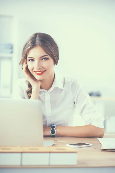 Aantrekkelijke zakenvrouw zit op een bureau met laptop in het kantoor — Stockfoto