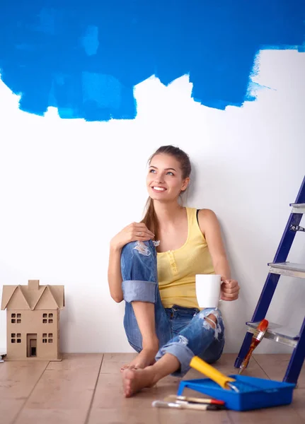 Porträt einer Malerin, die nach dem Malen auf dem Boden neben der Wand sitzt — Stockfoto