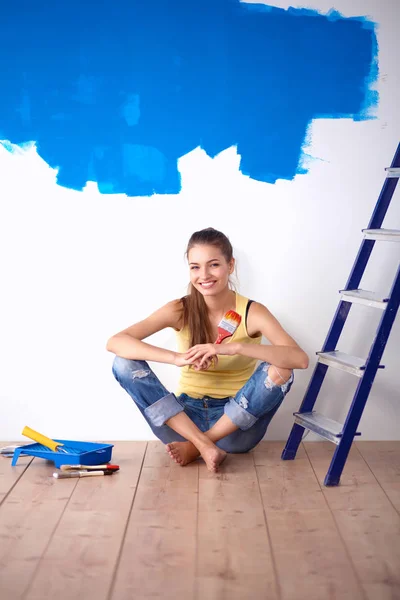 Porträt einer Malerin, die nach dem Malen auf dem Boden neben der Wand sitzt — Stockfoto