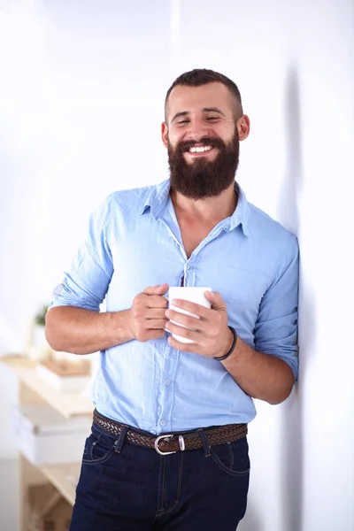 Jonge man permanent in de buurt van muur en houden kopje koffie — Stockfoto