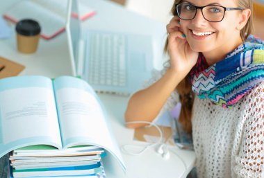 Kitapların arasında masa başında oturan genç bir kadın.