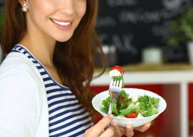 Salata yemek ve karışık salata tutan genç kadın