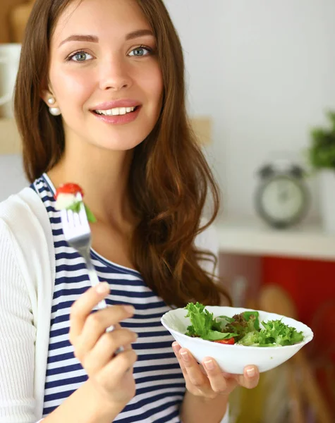 Mujer joven comiendo ensalada y sosteniendo una ensalada mixta — Foto de Stock