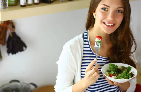 Jovem mulher comendo salada e segurando uma mistura — Fotografia de Stock