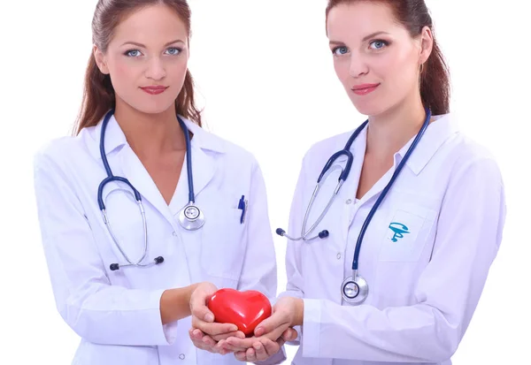 Δύο γυναίκες γιατρός κρατώντας μια κόκκινη καρδιά, απομονώνονται σε λευκό φόντο — Φωτογραφία Αρχείου