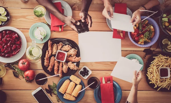 Top view of group of people having dinner together while sitting at wooden table — Stock Photo, Image