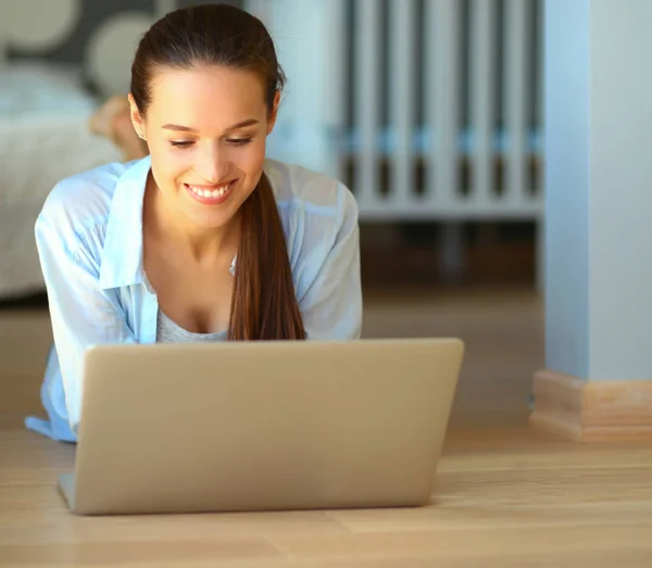 Unga vackra kvinnan hemma sitter på golvet med laptop — Stockfoto