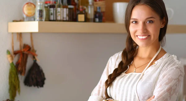 Mujer joven de pie cerca de escritorio en la cocina — Foto de Stock