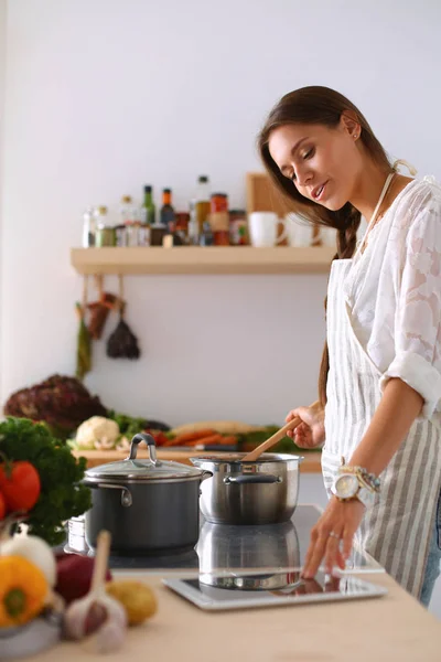 Young woman using a tablet computer to cook in her kitchen . — Stock Photo, Image