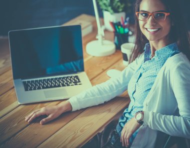 Masada oturan genç bir kadın.