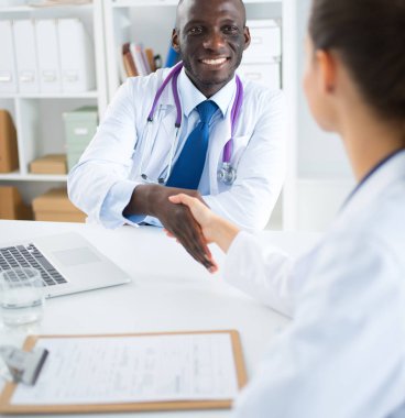 Ofiste tokalaşırken gülümseyen iki genç doktor.