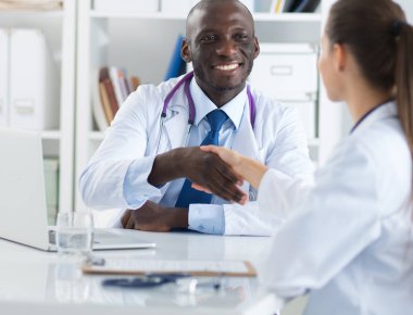 Ofiste tokalaşırken gülümseyen iki genç doktor.