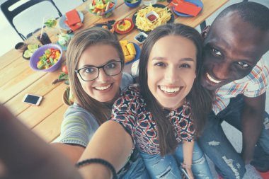 Öğle yemeği sırasında selfie çeken bir grup insan.