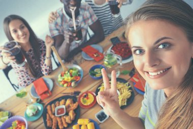 Öğle yemeği sırasında selfie çeken bir grup insan.