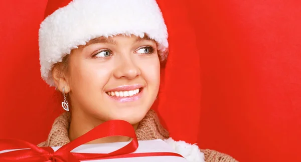 Santa girl holding Christmas gift on red background — Stock Photo, Image