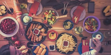 Öğle yemeği sırasında selfie çeken bir grup insan.