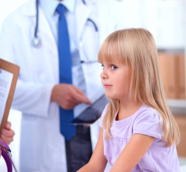 Kadın doktor ameliyatta steteskopla çocuğu muayene ediyor.