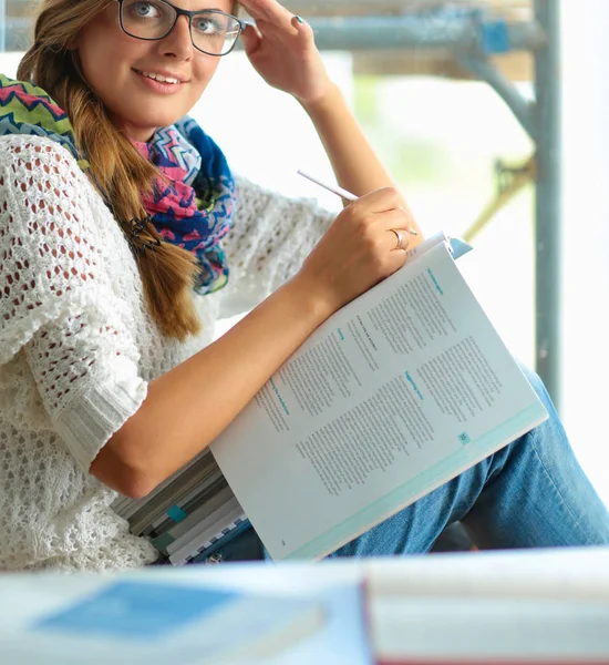 Lycklig student tjej sitter med högen av böcker — Stockfoto