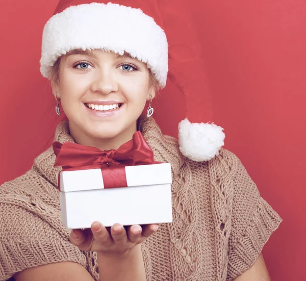 Santa girl holding Christmas gift on red background — Stock Photo, Image