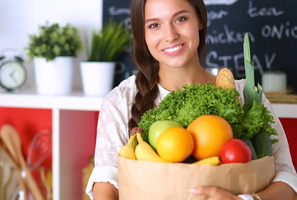 Ung kvinna som håller i matkassen med grönsaker — Stockfoto