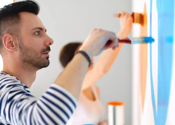 Portrait happy smiling young couple painting interior wall of new house — Stock Photo, Image