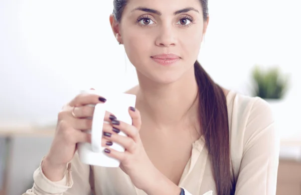 Молодая деловая женщина сидит на столе с чашкой — стоковое фото