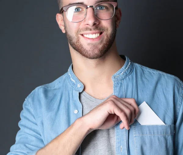 Young man holding a credit card standing on gray background. — Stock Photo, Image