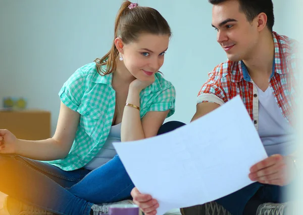 Junges Paar sitzt auf dem Boden und rechnet über seine Ersparnisse — Stockfoto