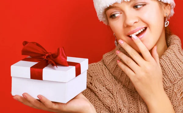 Santa girl holding Christmas gift on red background — Stock Photo, Image