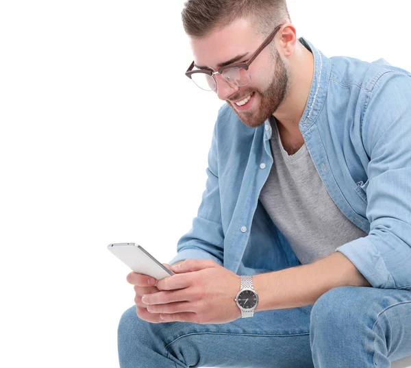 En ung kille med en mobiltelefon, isolerad på vit bakgrund — Stockfoto