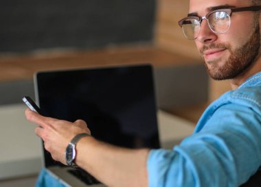 Genç adam kanepede otururken dizüstü bilgisayar ile çalışır