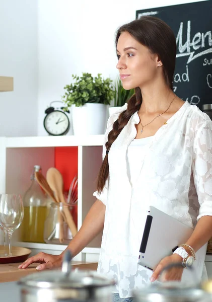 Mujer joven de pie cerca de escritorio en la cocina —  Fotos de Stock