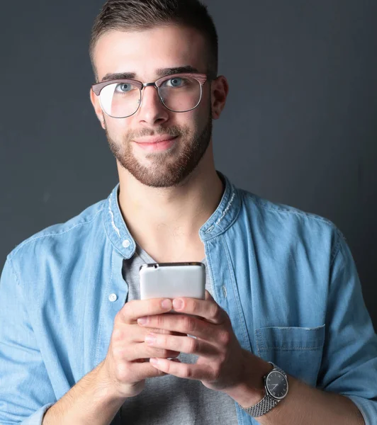 Sonriente joven sosteniendo el teléfono mientras envía mensajes de texto — Foto de Stock