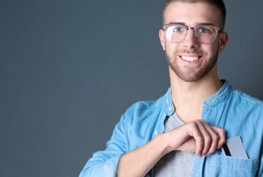 Genç adam gri arka plan üzerinde bir kredi kartı ayakta tutan
