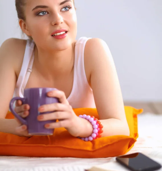 Smiling young woman lying on a white floor with pillow — Stock Photo, Image