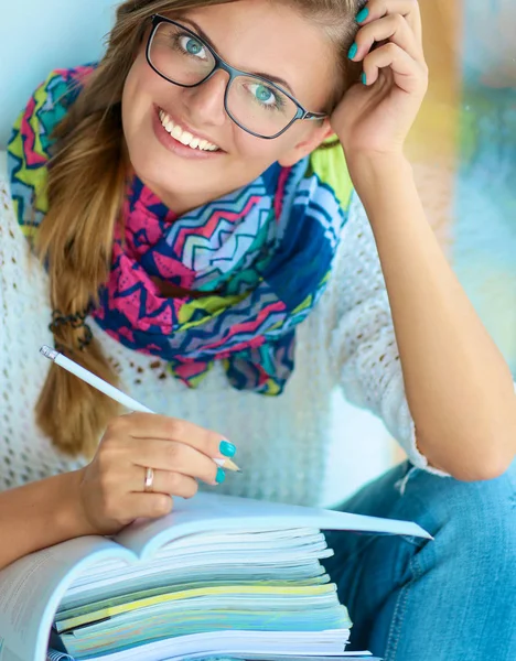 Gelukkig student meisje zit met stapel boeken — Stockfoto