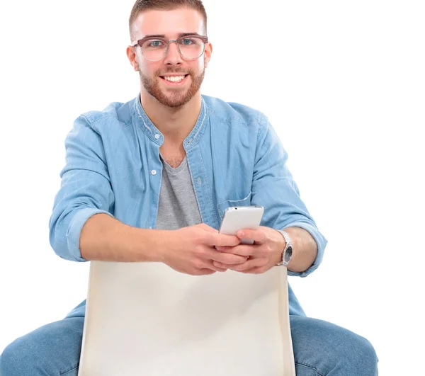 Jeune homme assis sur une chaise et utilisant un téléphone portable — Photo