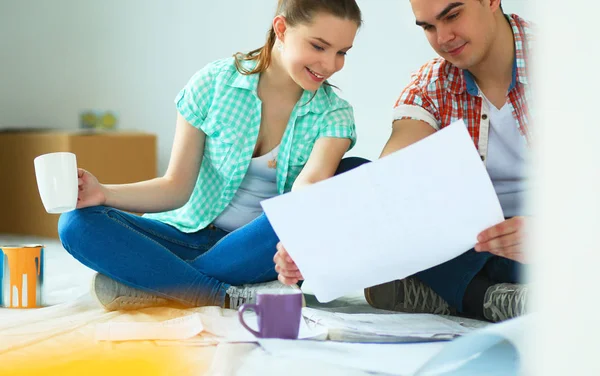 Man and woman looking at their house plans sitting in their new house — Stock Photo, Image