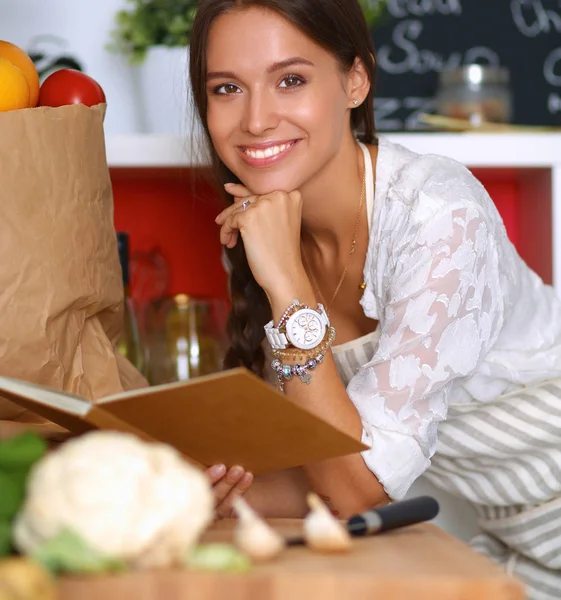 Giovane donna che legge il libro di cucina, alla ricerca di ricetta — Foto Stock