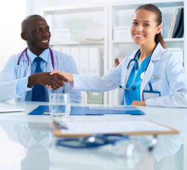 Ofiste tokalaşırken gülümseyen iki genç doktor.