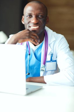 Masada dizüstü bilgisayarda çalışan genç bir Afrikalı doktor.