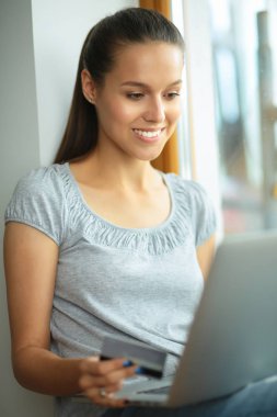 Genç ve güzel bir kadın evde dizüstü bilgisayar kullanıyor.