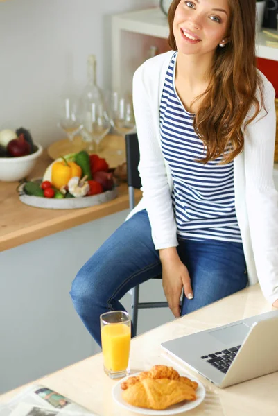 Ung kvinna sitter nära skrivbord i köket — Stockfoto